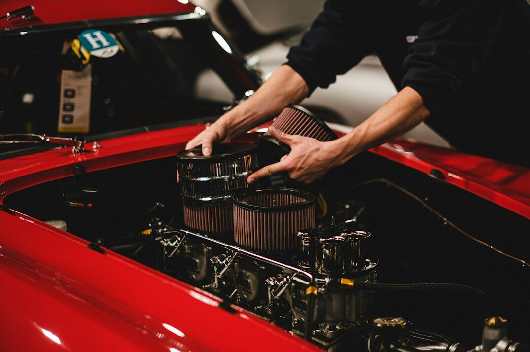 Specialist inspecting the engine details of a classic automobile with a notebook