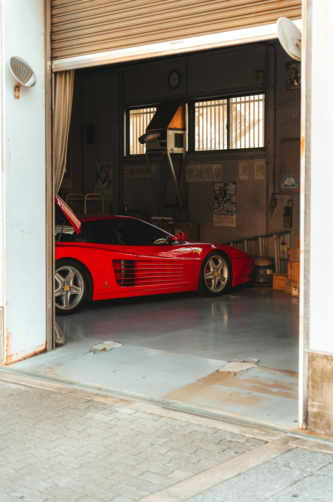 Dimly lit private garage housing several classic automobiles under dust covers
